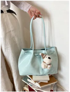 Light blue woven tote bag detail showing intrecciato texture and cute puppy charm accessory.