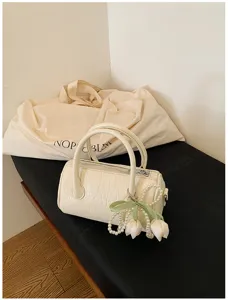 Detailed view of white barrel pillow bag with elegant pearl tulip pendant and top handle.