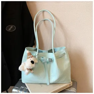 Close-up detail of mint green woven tote bag with cute bear pendant and side belt.