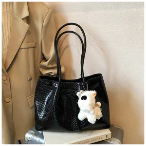 Close-up of black woven tote bag showing delicate leather texture, dual straps, and cute puppy charm.
