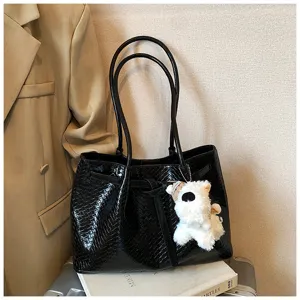 Black woven tote bag detail showing texture, double handles, and cute puppy plush pendant charm.