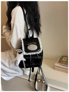 Black patent leather backpack with white lace trim, cute college style rucksack for travel.
