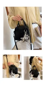Black leather top handle crossbody bag detail view featuring silver star charm and adjustable strap.