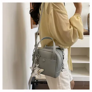 Detail view of the gray casual crossbody handbag featuring a stylish star charm and dual handles.