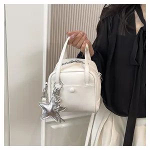 Detailed view of white leather handbag with star charm, stylish casual crossbody design.