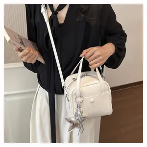 Detailed view of white leather crossbody bag, featuring textured finish and star charm.