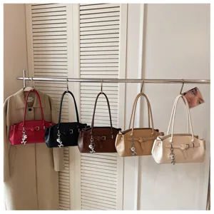 Detail view of stylish multi-color shoulder bags hanging on rack with metallic floral charm.