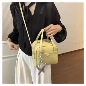 Chic yellow leather crossbody shoulder bag detail featuring star charm and double top handles.