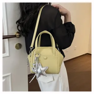 Close-up detail shot of the stylish yellow shoulder bag featuring a chic silver star charm.