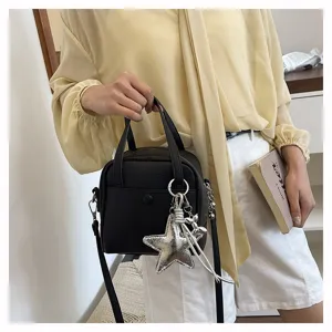 Detail view of the black leather handbag featuring a stylish silver star pendant and handle.