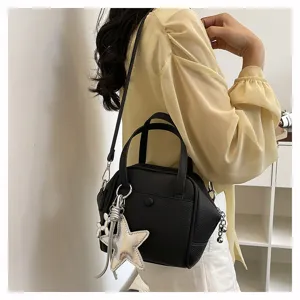 Detail view of a black leather shoulder bag with silver star pendant and chic chain charms.