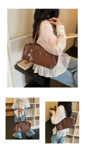 Detail view of the brown leather shoulder bag featuring stylish belt decoration and charm.