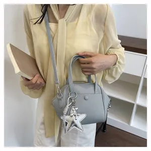 Detailed view of the stylish grey top handle shoulder bag with charming star pendant in use.