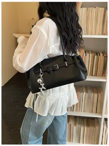 Stylish black shoulder underarm bag for women, trendy commuter PU leather handbag with chic pendant.