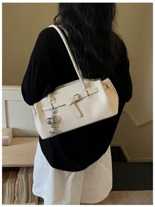 Chic white leather shoulder bag detail with metal buckle and cute charm accessory.