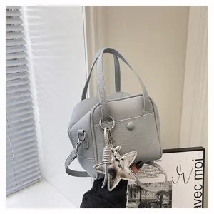 Detailed view of the grey textured handbag featuring stylish top handles and a shiny star charm.
