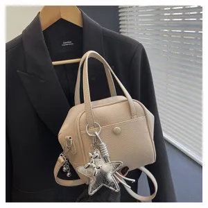 Beige leather texture handbag detail, elegant shoulder crossbody bag with metallic star charm.