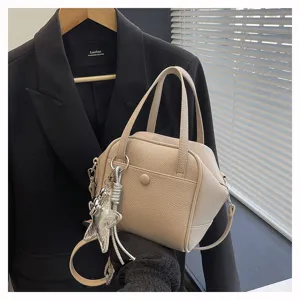 Detail view of a chic beige structured crossbody shoulder bag with a stylish star pendant.