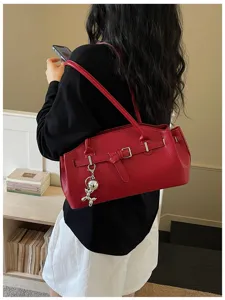 Chic red leather shoulder bag for women, stylish underarm handbag with metal buckle and charm.