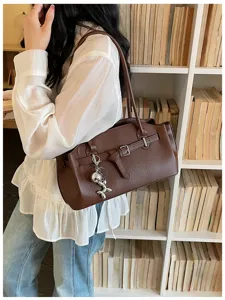 Brown leather shoulder bag for women, stylish underarm bag with metal buckle and cute charm.