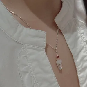 Primo piano dettaglio di una collana con ciondolo gelato in argento con perle di pietra.