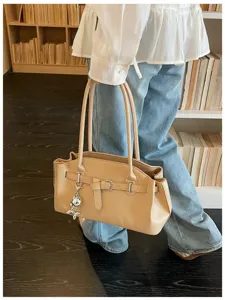 Detailed showcase of elegant beige leather handbag featuring a chic metal balloon charm and stylish belt.