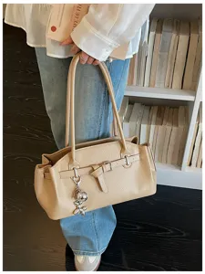 Stylish beige shoulder bag for women, chic textured PU leather tote with belt detail and pendant.