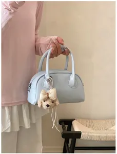 Close-up of light blue baguette handbag with cute puppy plush charm for casual daily wear