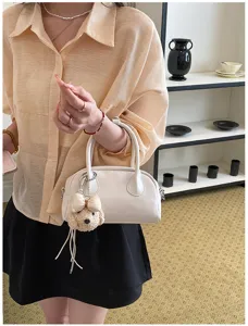 Detail shot of a stylish white handbag with a cute puppy plush charm, elegant and chic.