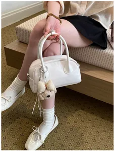 Detailed view of the stylish white baguette shoulder bag with cute bear plush keychain.