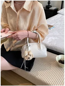 Detail view of the stylish white shoulder bag with a cute puppy plush pendant, elegant design.