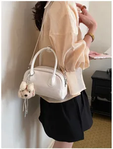Chic white handbag detail showing structured design and cute puppy plush charm accessory.
