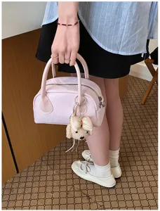 Detail view of stylish pink handbag with cute puppy keychain, casual everyday accessory.