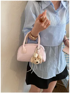 Close-up of stylish pink handbag with cute puppy plush keychain, lifestyle fashion detail view.