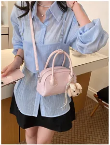 Detailed view of women casual pink shoulder bag with cute dog pendant and smooth texture.