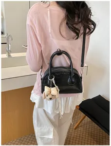 Stylish black dome handbag with cute plush puppy pendant, versatile shoulder and crossbody bag.