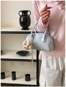 Close-up detail of light blue handbag featuring cute plush bear charm and sleek design.