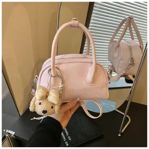 Pink leather shoulder handbag with cute puppy plush charm, stylish daily casual baguette bag.