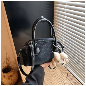 Black women handbag detail featuring premium texture and stylish design with a cute bear pendant.