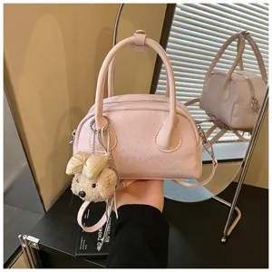 Pink patent leather shoulder handbag for women, chic baguette bag with cute bear charm.