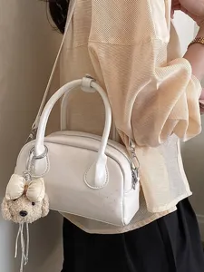 Fashionable white top handle handbag with cute puppy plush keychain, minimalist chic design for women.