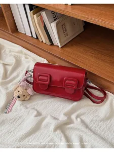 Red vintage style cross body small square shoulder bag with cute teddy bear plush keychain decor.