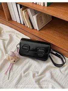 Close-up detail of the black glossy vintage shoulder bag with cute bow bear pendant charm.