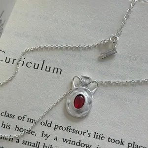 Primo piano dettagliato della collana con ciondolo in argento vintage e gemma rossa.
