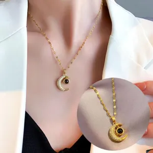 Detail view of gold-tone crescent moon pendant necklace with sparkling rhinestones.