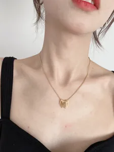 Gros plan détaillé d'un collier minimaliste vintage doré à plusieurs pendentifs sur la clavicule.
