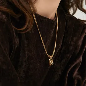 Detailaufnahme einer eleganten 18K vergoldeten geometrischen Herz-Halskette am Model.