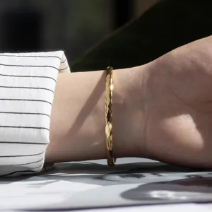 Detailed view of the elegant diamond cut titanium steel gold bracelet worn on the wrist.