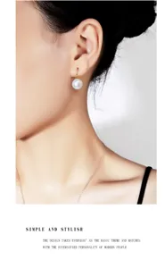 Nahaufnahme einer eleganten Perlenohrring am Modell, zeigt glatten Glanz und Silberhaken.