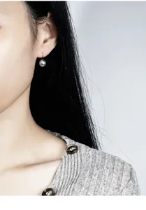 Nahaufnahme Detailansicht einer eleganten grauen Perlenohrring an Silberhaken, Schmuck.